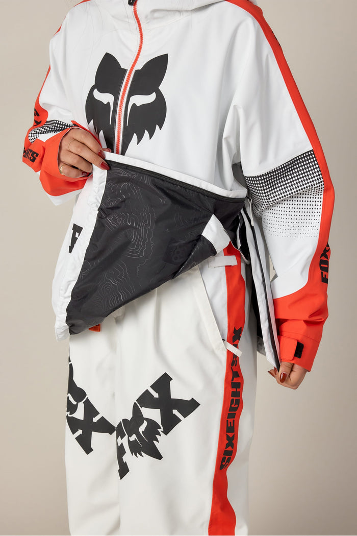 A person wearing the 686 Women's Fox Racing Shell Anorak, showing its black patterned inner lining, is visible from the lower face and body.