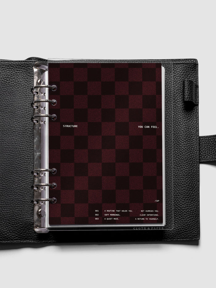 A5 sized velvet checkered dashboard in the color Bordeaux with crystal clear planner dashboard shown inside a black leather agenda.