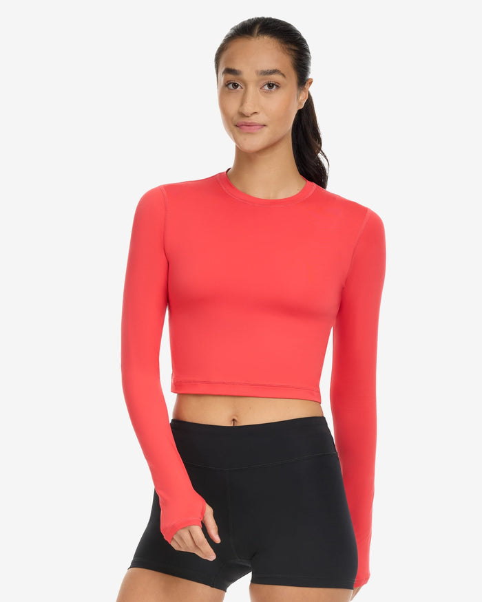A woman wearing a red extended body length crop top on a white background