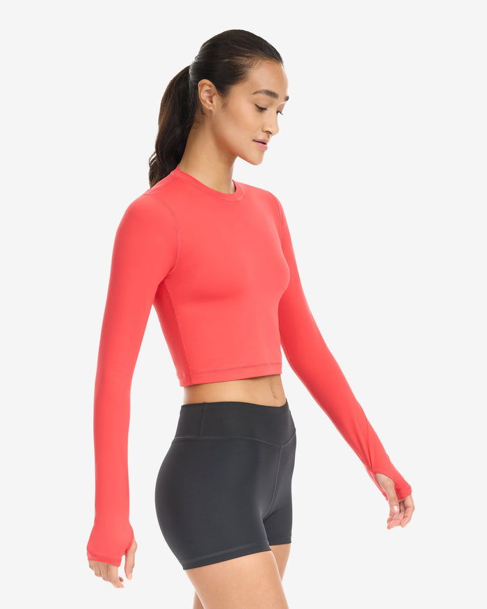 A woman wearing a red extended body length crop top on a white background