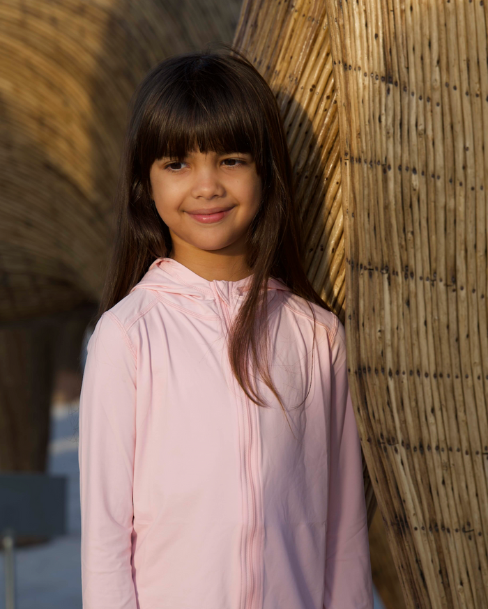 A girl wearing a pink full zip hoodie top with long sleeves, suitable for kids.