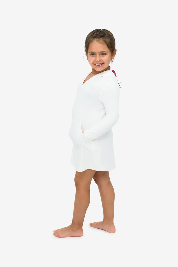 Young girl in a white dress standing against a white background