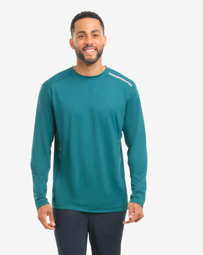 Man wearing a jungle green long-sleeve shirt and black pants on a white background