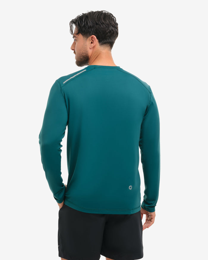 Person wearing a teal long-sleeve athletic shirt and black shorts on a white background