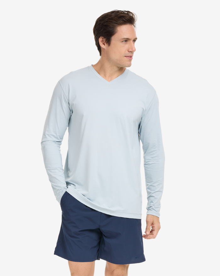 A man wearing a gray long-sleeved V-neck shirt, on a white background.