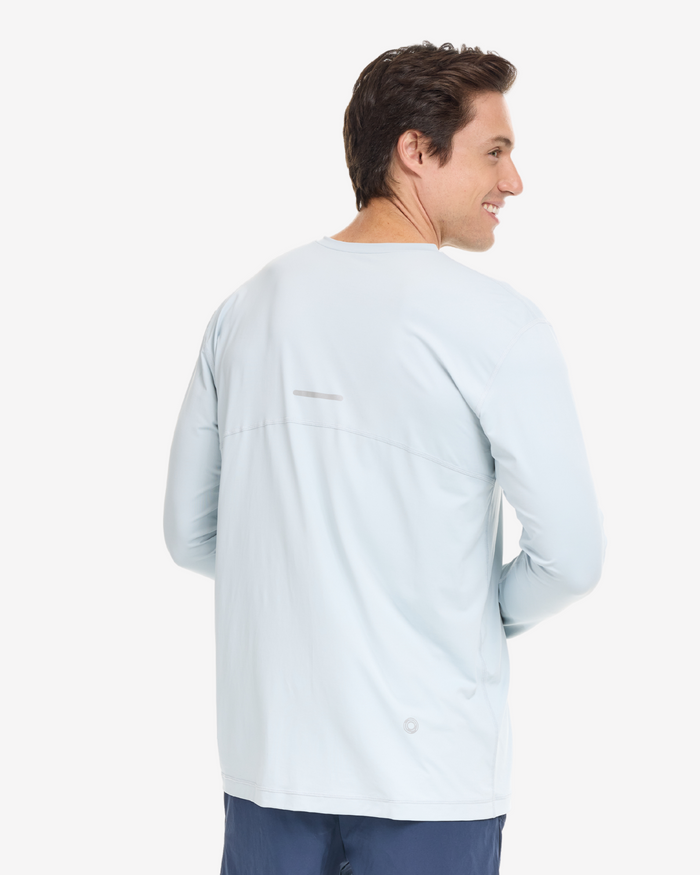 A man wearing a gray long-sleeved V-neck shirt, on a white background.
