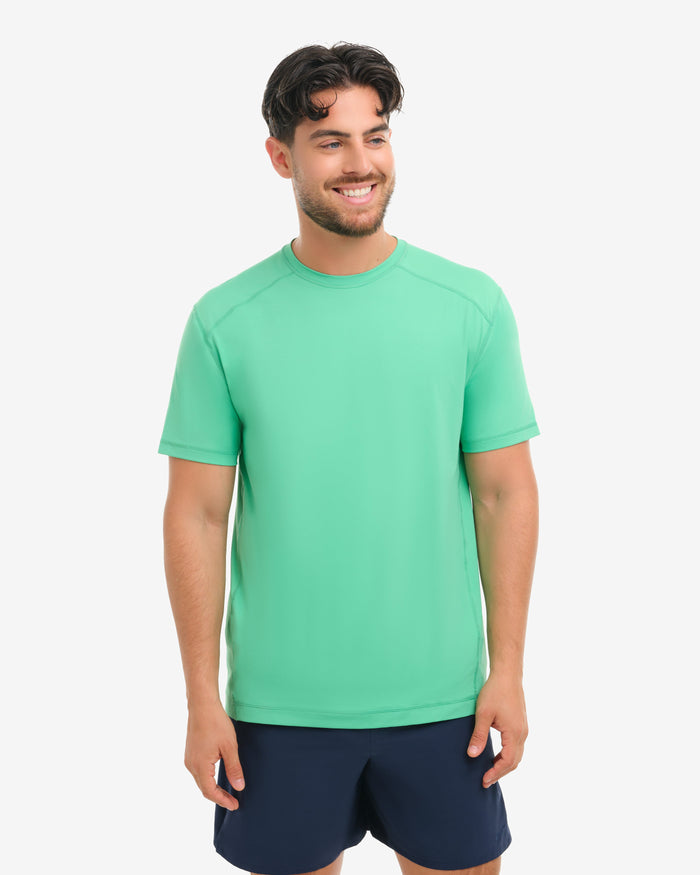 Man wearing a green s shirt and navy shorts on a white background