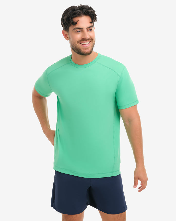 Man wearing a green shirt and navy shorts on a white background