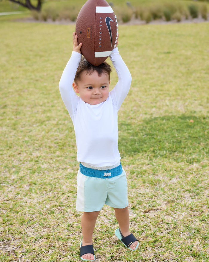 Child holding a football in an outdoor setting