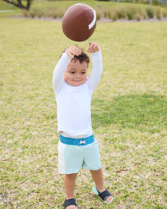 Child holding a football in a grassy field