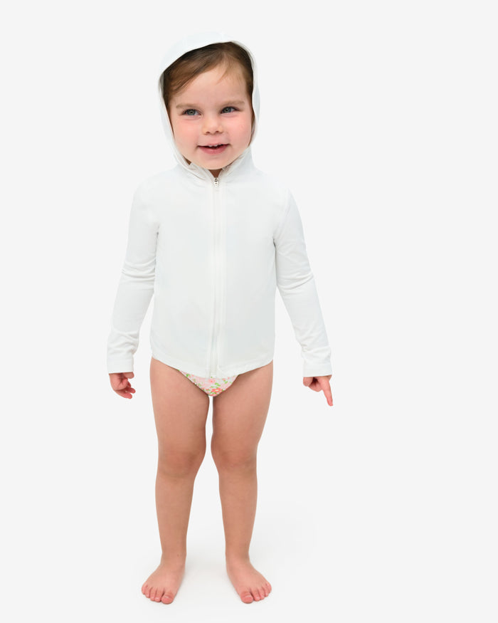 A toddler wearing a long sleeve full zip hoodie top in white on a white background