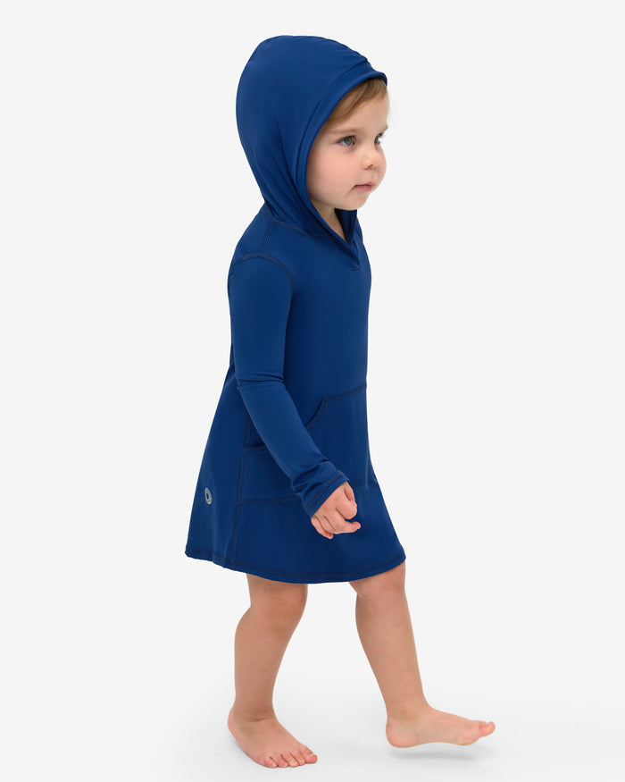 A toddler in a blue hoodie dress with long sleeves and a hood, standing against a white background.