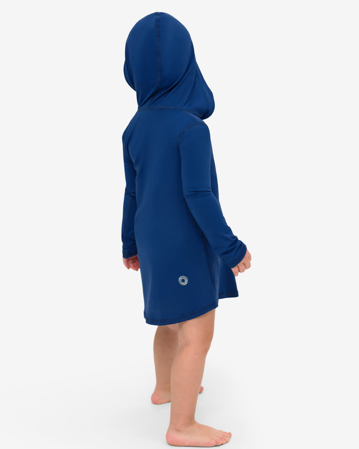 A toddler in a blue hoodie dress with long sleeves and a hood, standing against a white background.
