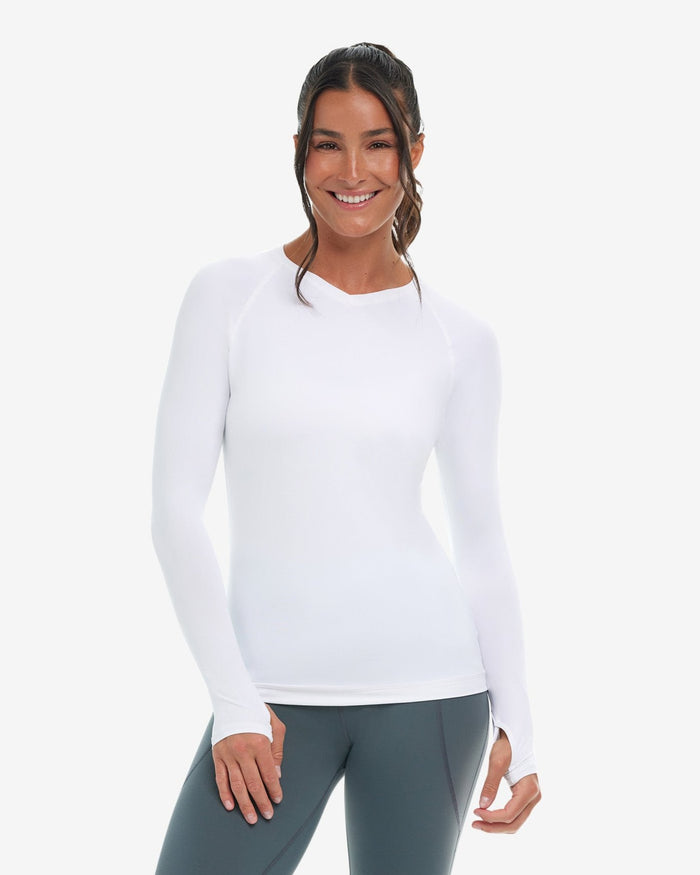 A woman wearing a white long-sleeved V-neck activewear top with thumbholes, on a white background.