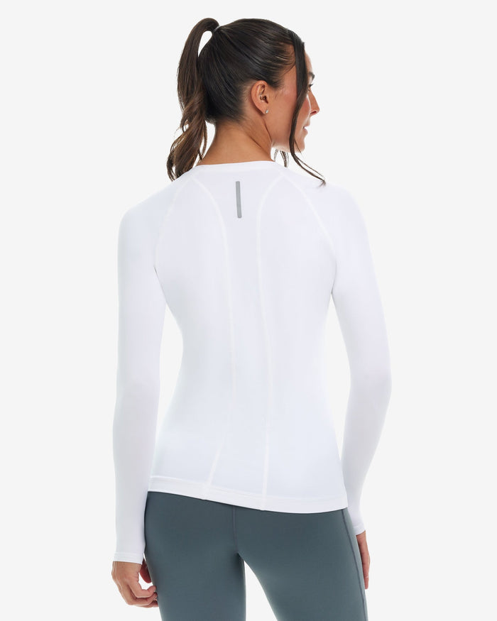 A woman wearing a white long-sleeved V-neck activewear top with thumbholes, on a white background.